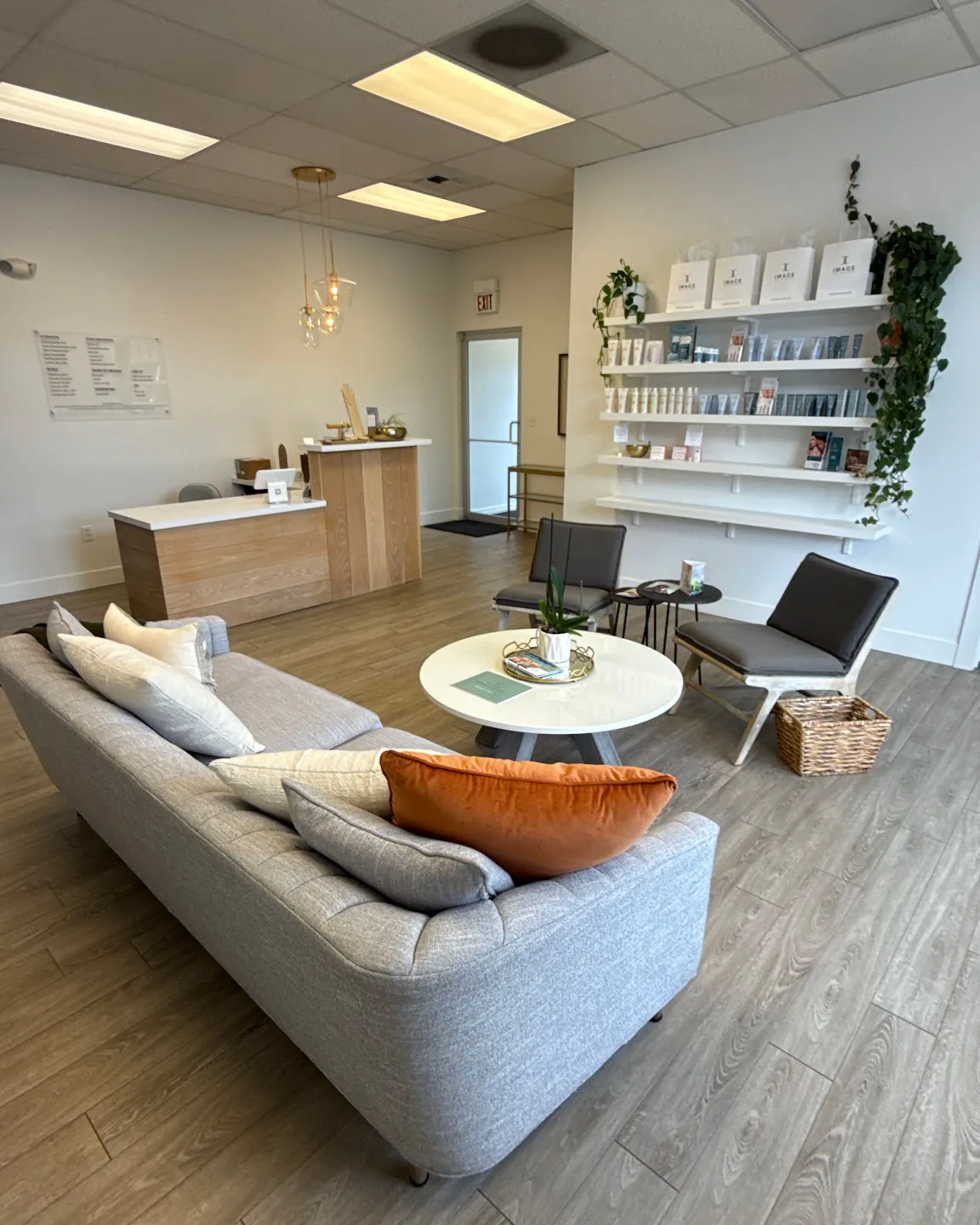 The reception lounge at Pomalo Wellness — a soft grey sofa, round white table and shelves of skincare at 401 S Orange St.