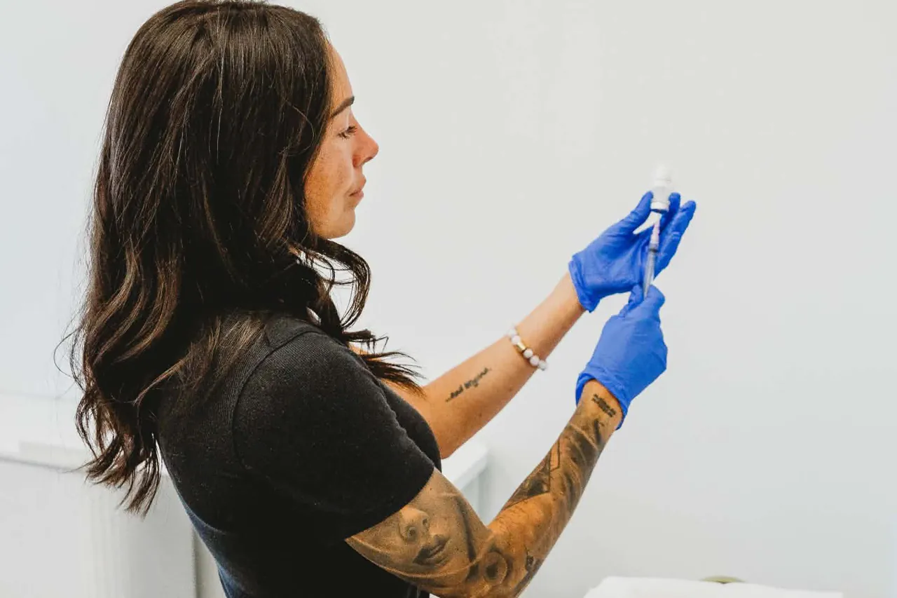 Clare Bourdon preparing a treatment at her cart, gloved, in the clinic.